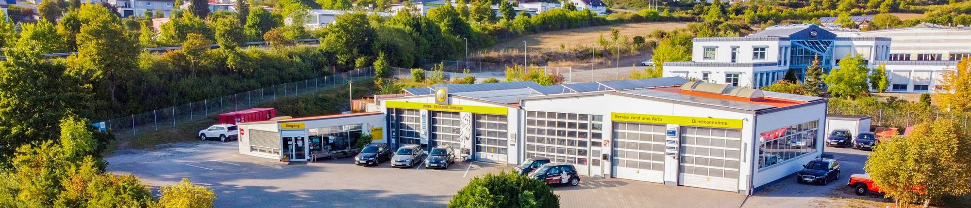 Eine Luftaufnahme des Firmengeländes von Auto-Elektrik Müller mit Werkstatt, Empfangsbereich und Parkplatz.